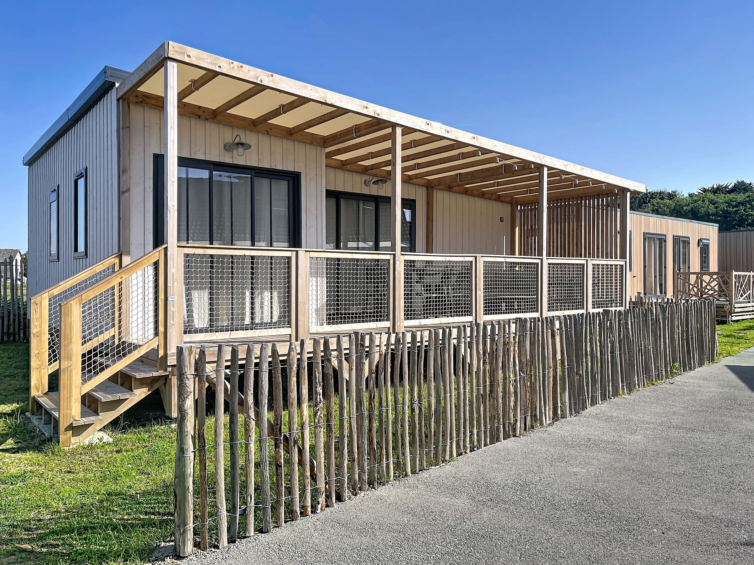 Un edificio moderno con rivestimento in legno, un portico coperto e un'area recintata.