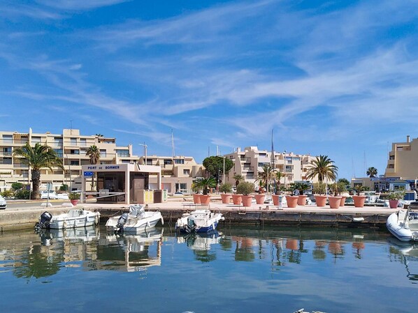 Ein Yachthafen mit vertäuten Booten, ein Gebäude mit der Aufschrift 'PORT DE BORMES' und Palmen.