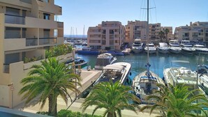 Un port de plaisance avec des bateaux, un immeuble doté de balcons et des palmiers.
