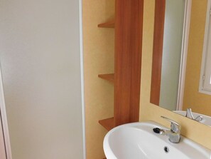 A bathroom with a white sink, a mirror, and a wooden panel on the wall. - Mobile home, pets allowed - 5 guests (Vesseaux)