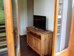 Ein Holz-TV-Möbel mit Fernseher, Fernbedienung und einem kleinen Schrank.
