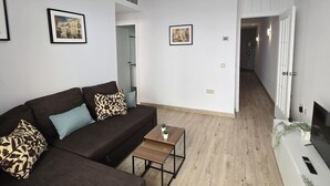 Un salon moderne avec un canapé, une petite table et un couloir menant à une porte.