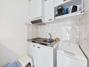 Een kleine keuken met een spoelbak, fornuis en een wasmachine.