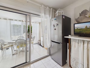 Eine moderne Küche mit Kühlschrank, Fernseher und Essbereich mit Stühlen und Tisch.