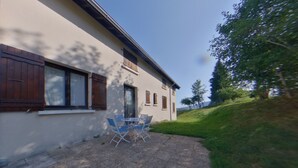 A building with a patio area featuring a table and chairs. - Charming apartment - 4 guests (Prémanon)