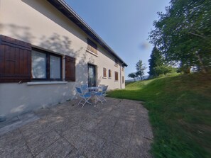Ein Gebäude mit einer Terrasse, komplett mit Tisch und Stühlen.