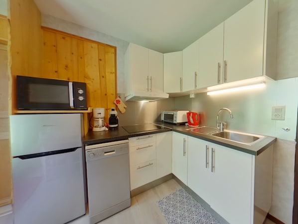 Una cocina compacta equipada con microondas, cafetera, tostadora y pileta.