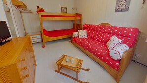Una habitación con literas, un sofá, una mesita y un televisor.