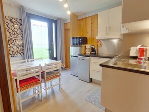 A modern kitchen with wooden cabinets, a built-in microwave, a coffee machine, and a dishwasher. - Charming apartment - 4 guests (Prémanon)
