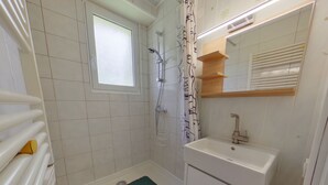 Un baño con bañera, ducha, ventana, lavabo y espejo.