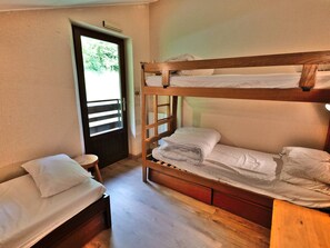 Una habitación con una cama literera, una cama individual y un taburete pequeño.