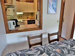 Cocina compacta con una mesa de madera, sillas y un espejo que refleja el ambiente.
