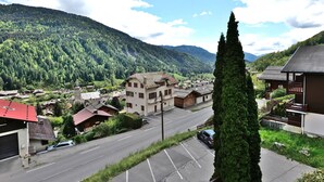 A residential area with a road, buildings, and a mountainous backdrop. - Pleasant duplex with view - 6 guests (Le Grand-Bornand)