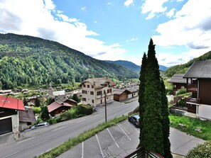 A residential area with a road, buildings, and a mountainous backdrop. - Pleasant duplex with view - 6 guests (Le Grand-Bornand)