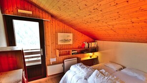 A cozy room with wooden walls, a bunk bed, a desk with books, and a small heater. - Pleasant duplex with view - 6 guests (Le Grand-Bornand)