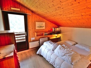 A cozy room with wooden walls, a bunk bed, a desk with books, and a small heater. - Pleasant duplex with view - 6 guests (Le Grand-Bornand)
