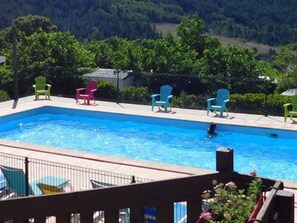 Una piscina con sillas a su alrededor, rodeada de vegetación.