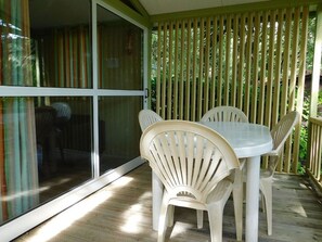 Eine Terrasse mit einer Glasglastür, die zu einem überdachten Bereich führt, einem runden Tisch und vier Stühlen.