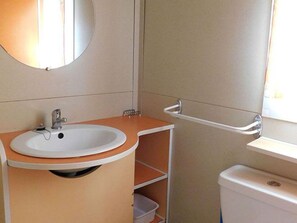 Ein Badezimmer mit Waschbecken, Spiegel, Toilette und einem Fenster.
