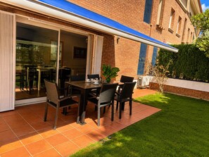 An outdoor patio with a table and chairs, a potted plant, and a brick building in the background. - Villa with pool & AC, near the sea - 6 guests (Platja d'Aro)
