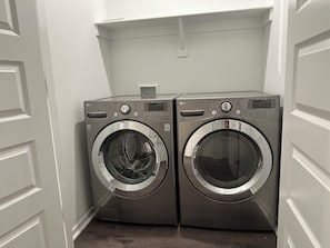 Dos lavadoras LG de carga frontal en un cuarto de lavado con paredes blancas y piso de madera.