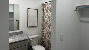 Ein Badezimmer mit Toilette, Waschbecken, Spiegel und einem gerahmten Motivationsspruch an der Wand.