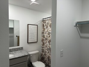 A bathroom with a toilet, sink, mirror, and a framed inspirational quote on the wall.