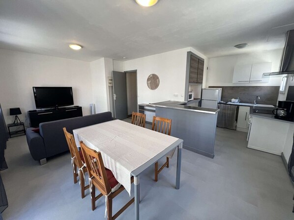 A modern apartment with a dining area, kitchen, living room, and a flat-screen TV. - Apartment in city center, small sea view - 4 guests (Valras-Plage)