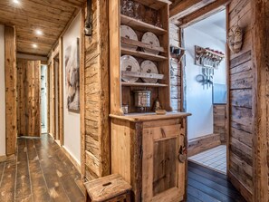 A rustic wooden interior with a wooden cabinet, shelves with dishes, and a small stool. - Ski-in/Ski-out apartment - 4 guests (Courchevel 1850)