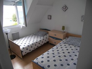A small, well-lit bedroom with two single beds, a nightstand, a lamp, and a window. - Cottage with garden and pool - 4 guests (Dives-sur-Mer)