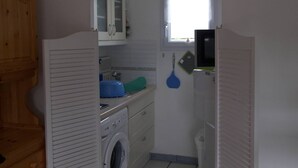 A compact laundry room with a washing machine, cabinets, and a window. - Cottage with garden and pool - 4 guests (Dives-sur-Mer)