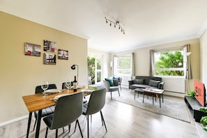 Ein modernes Wohnzimmer mit Essbereich, großen Fenstern und Blick ins Grüne.
