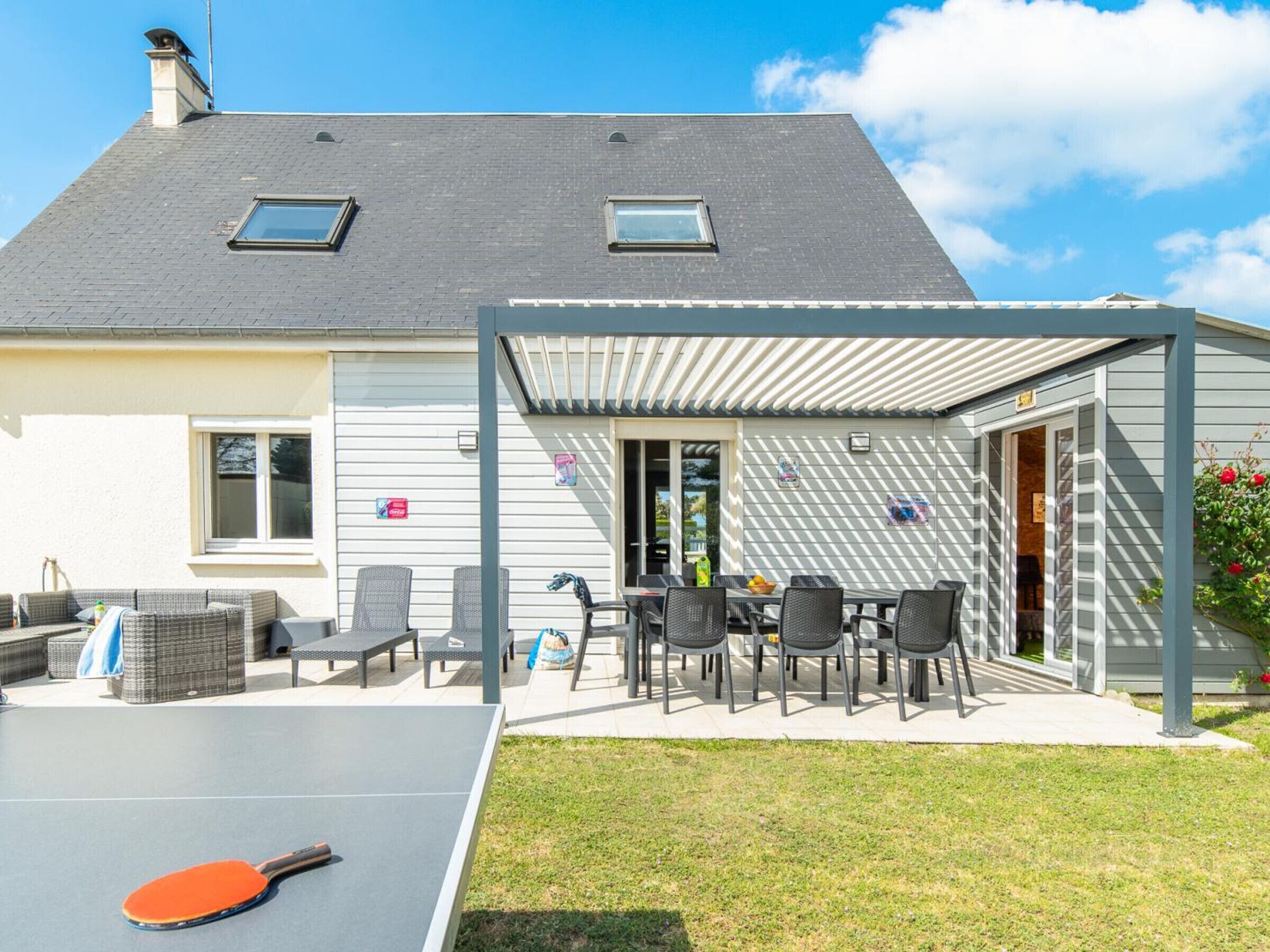 Une maison dotée d’un patio couvert, d’un espace salon extérieur et d’une table de ping-pong.