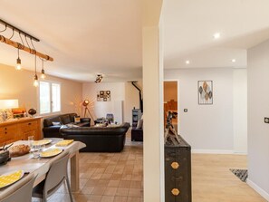 A modern living room with a sofa, dining table, and a staircase leading to another level.