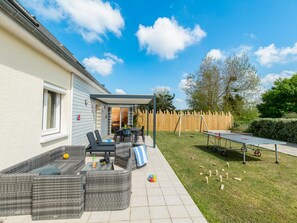 A patio with outdoor furniture, a ping pong table, and a wooden fence.