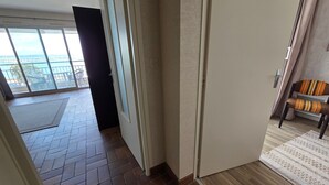 Un pasillo con vista a un balcón, una puerta y una silla.