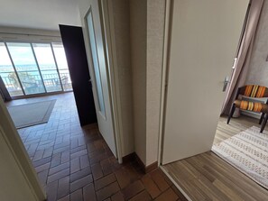 A corridor with a view to a balcony, a door, and a chair. - Apartment with port view - 4 guests (Jard-sur-Mer)