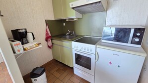 Una cocina compacta equipada con estufa, microondas y un refrigerador pequeño.
