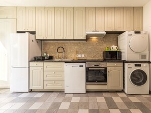 A modern kitchen with built-in appliances, including a dishwasher, oven, and washing machine. - Peaceful cottage in the countryside, pets welcome (GUENROUET)