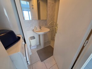 Un bany compacte amb un lavabo, mirall i dutxa.