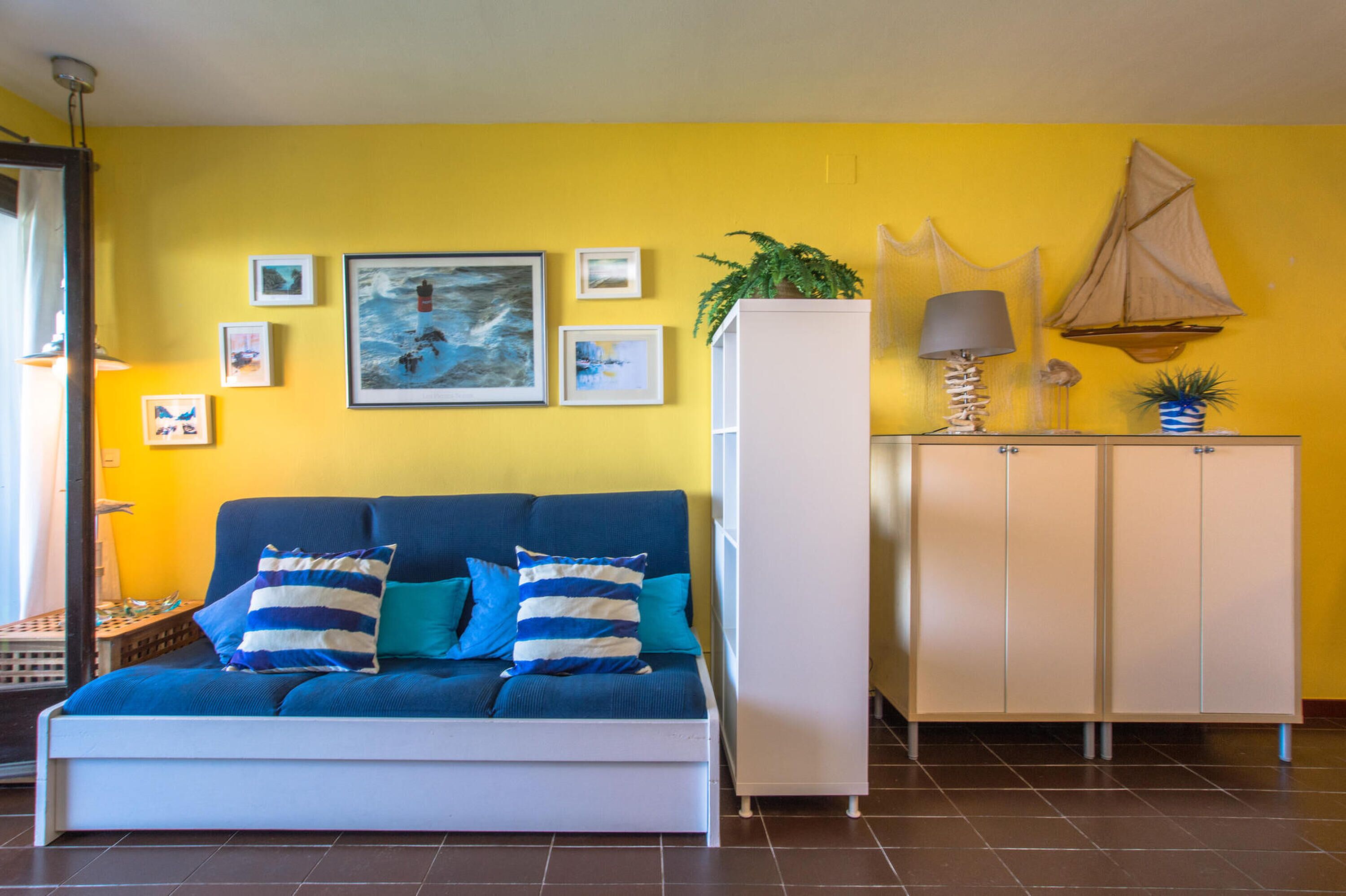 A room with a sofa, a cabinet, and a wall with framed pictures.
