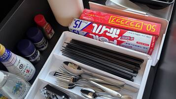 Un cajón con utensilios de cocina ordenados, incluyendo palillos, cucharas y una tetera.