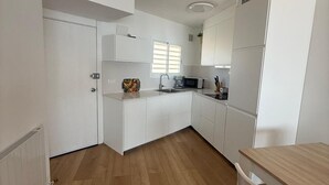 Een moderne keuken met witte kasten, een houten aanrecht, een magnetron en een spoelbak.