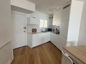 A modern kitchen with white cabinets, a wooden countertop, a microwave, and a sink. - Apartment with sea view - 3 guests (San Antonio de Calonge)