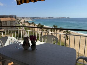 A balcony with a table, chairs, and a view of the beach and ocean. - Apartment with sea view - 3 guests (San Antonio de Calonge)