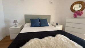 Een slaapkamer met een bed, nachtkastjes, een kaptafel, een spiegel en een zacht tapijt.