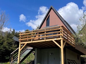 Ein Gebäude mit einer Holzterrasse, einer Treppe und einer Garagentür.