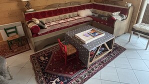 A cozy room with a sofa, a small table, a chair, a mirror, and a window. - Comfortable apartment for 8 guests with private garage (Les Gets)