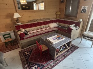 Ein gemütliches Zimmer mit einer Couch, einem kleinen Tisch, einem Stuhl, einem Spiegel und einem Fenster.