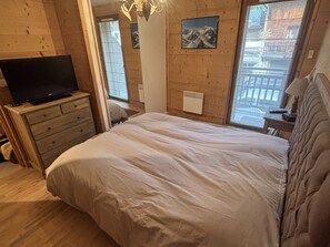 Ein Schlafzimmer mit einem Bett, einem Schminktisch, einem Fernseher, einer Heizung und einem Fenster mit Blick.